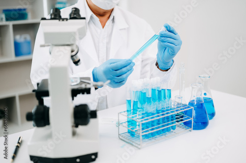 Scientists conducting research investigations in a medical laboratory  a researcher in the foreground is using a microscope in laboratory for medicine.  .