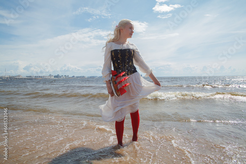 Young blonde model woman standing on sea beach, romantic portrait photo