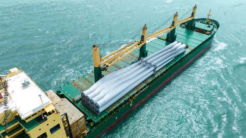 Wind Turbine on Ship, Transportation of blades for wind turbines on a cargo ship. Heavy load carrier on cargo ship loaded with Electric Wind Turbine Blades. © Yellow Boat