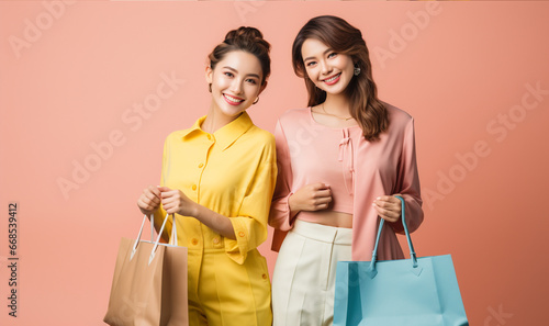 Two trendy asian woman holding shopping bags. laughing and enjoying.