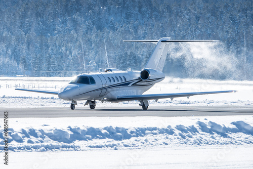Luxury business jet taking off in engadin valley in the Swiss alps. The airport of Samedan is used by wealthy people to get to their ski vacations in winter. This airplane did no de-icing before dep. photo