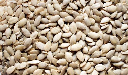 Background with raw hulled pumpkin seeds close-up