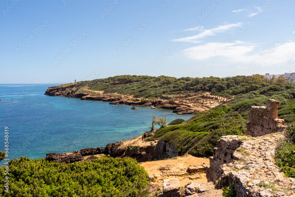 Wide angle panorama of the ruins of the Roman Archeological Park of Tipaza ( Tipasa ), Algeria. Green trees and spring maritime flowers.