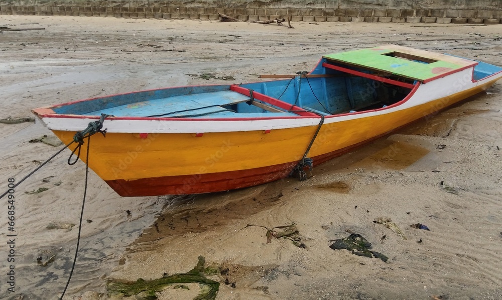 an orange fishing boat rests on a receding beach an orange fishing boat rests on a receding beach
