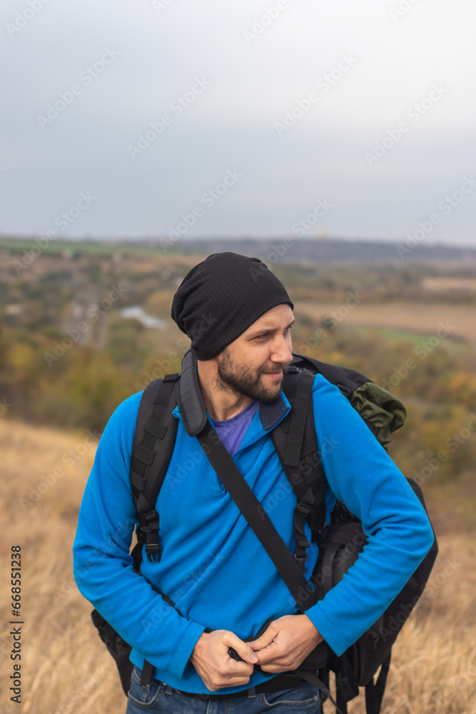 A man tourist hiker climber with a backpack behind his back stands against the backdrop of a beautiful landscape A man tourist hiker climber with a backpack behind his back stands against the backdrop of a beautiful landscape