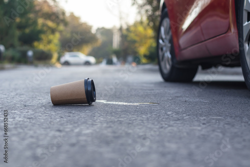 Waste coffee cup thrown on the road by a car driver.Environmental pollution concept