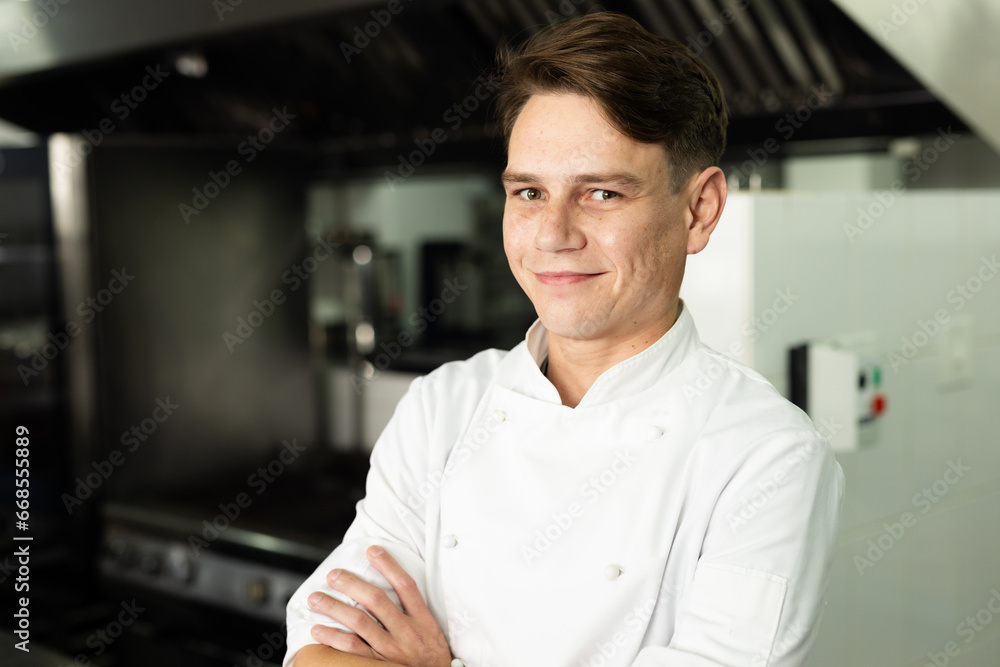 Portrait of smiling caucasian male chef with arms crossed standing confidently in kitchen Portrait of smiling caucasian male chef with arms crossed standing confidently in kitchen