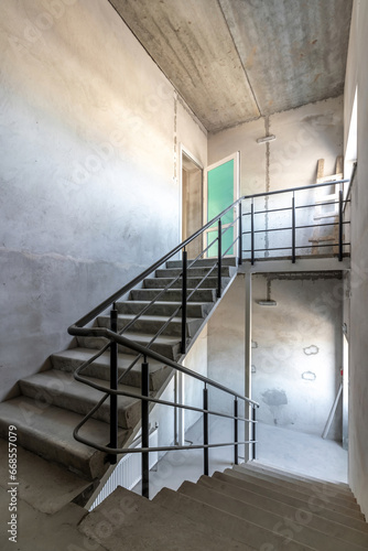Reinforced concrete staircase with black metal pyrils in a new concrete building
