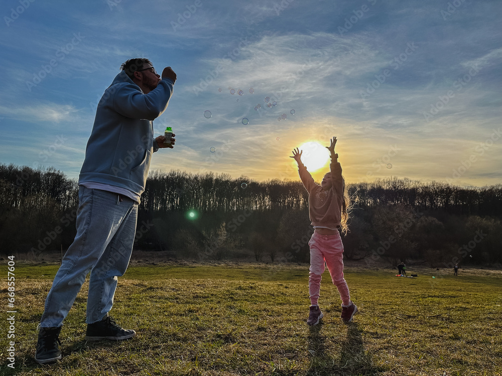happy man with little girl playing with soap bubbles happy man with little girl playing with soap bubbles