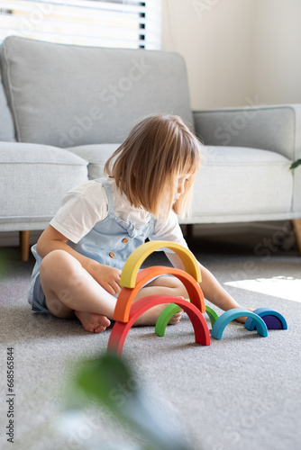 A cute girl is playing an educational game with a wooden rainbow. child development  © Виктория Попова