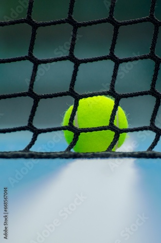 selective focus on a ball behind the net on a tennis or paddle tennis court, racket sports backdrop