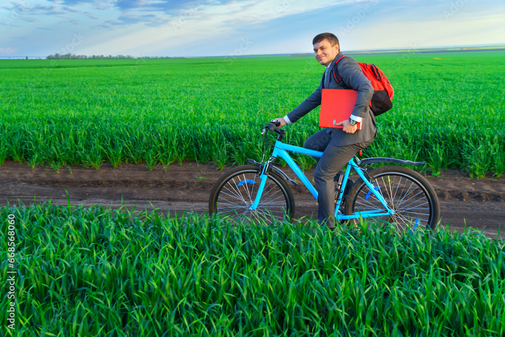 businessman rides a bicycle through a green grass field, the concept of activity, leisure or freelancing businessman rides a bicycle through a green grass field, the concept of activity, leisure or freelancing