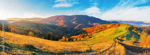panorama of carpathian countryside landscape at sunrise in autumn. rolling scenery with rural fields and forested hill in morning light. distant ridge beneath s sky with clouds