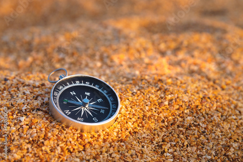 the compass lies on the golden sand, on the beach of shells on a sunny day