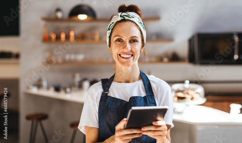 Successful cafe owner using a tablet to manage her small business photo