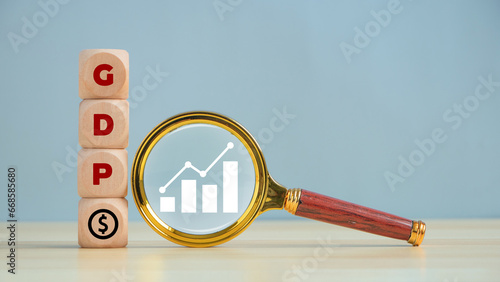 Word 'GDP' on block and magnifying glass with Growth arrow chart. Gross domestic product, Financial, Management, Economic, Inflation, recession and Money concepts. Government budget, public spending. photo