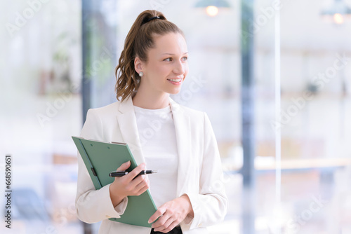 Beautiful and smiling businesswoman with paperwork in her hands standing in the office.
