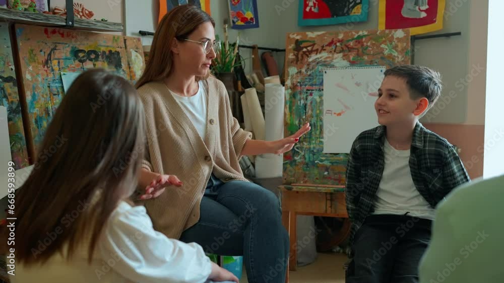 Charming teacher talking with children during an illustration class at art school Charming teacher talking with children during an illustration class at art school