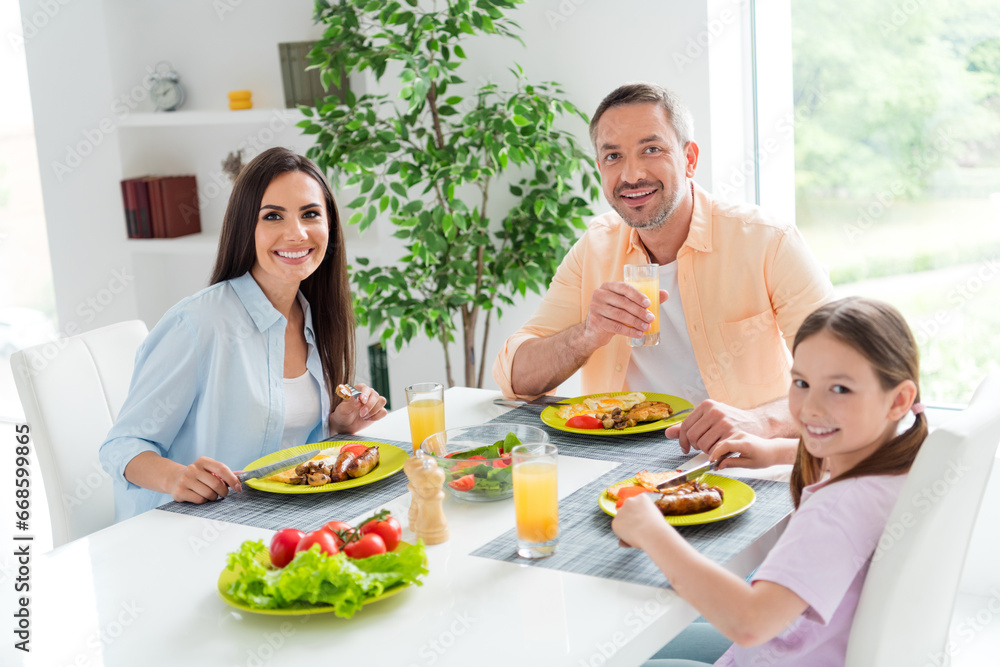 Photo of peaceful idyllic people toothy smile sit kitchen table eat tasty food drink fresh juice spend pastime flat inside