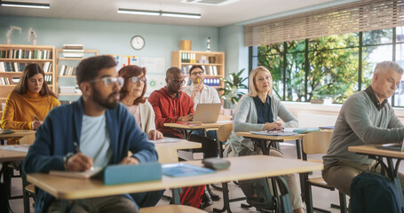 Diverse Mature Students Learning in Classroom, Using Laptops and Writing in Notebooks. Male And Female Class Attendees Listening to Lecture And Taking Notes During Adult Education Course in School