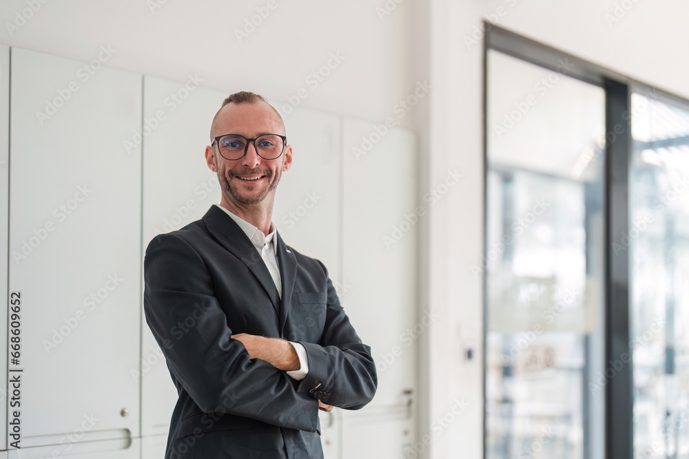 Portrait of an attractive young businessman A successful business executive stands with his arms crossed in his office with a happy smile on his face. Portrait of an attractive young businessman A successful business executive stands with his arms crossed in his office with a happy smile on his face.