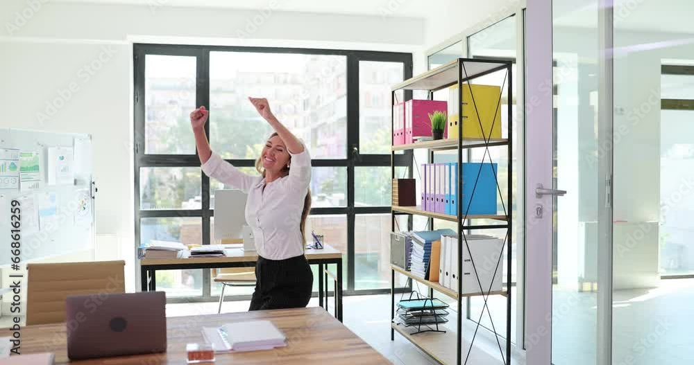 Happy joyful young and attractive woman dancing victory dance in office. Female office worker having fun celebrating achievement and winning dance Happy joyful young and attractive woman dancing victory dance in office. Female office worker having fun celebrating achievement and winning dance