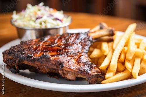 slightly blurred image of bbq ribs, focusing on coleslaw and fries
