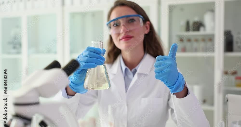Scientist holds clear clean water in flask and shows thumbs up. Analysis and testing of water concept approved filters Scientist holds clear clean water in flask and shows thumbs up. Analysis and testing of water concept approved filters