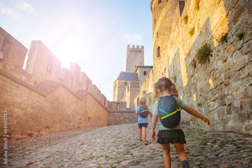 Kids hurry to explore Carcassonne castle walls at summer sunset - obrazy, fototapety, plakaty 