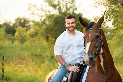 a young guy in a white shirt sits on a horse, a guy walks with his horse through the forest