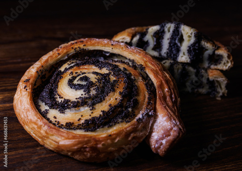 Two poppy seed buns whole and cut on a wooden background. photo