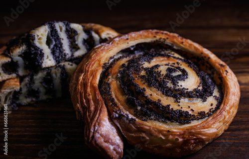 Two poppy seed buns whole and cut on a wooden background. photo