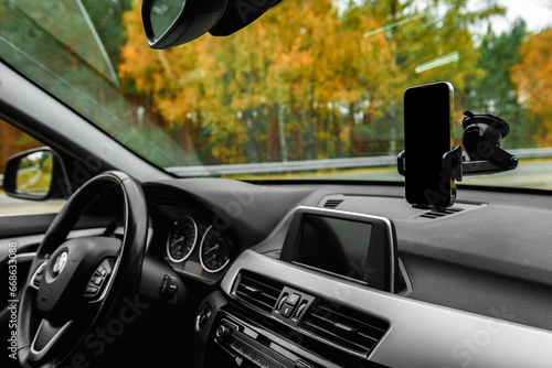 Car holder with mobile phone with black screen on windshield of car. photo