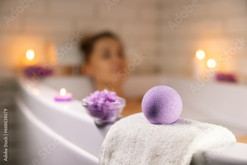 home spa. woman relaxing in bathtub in candle light and using bath bomb and sea salt crystals for body skin moisturizing photo