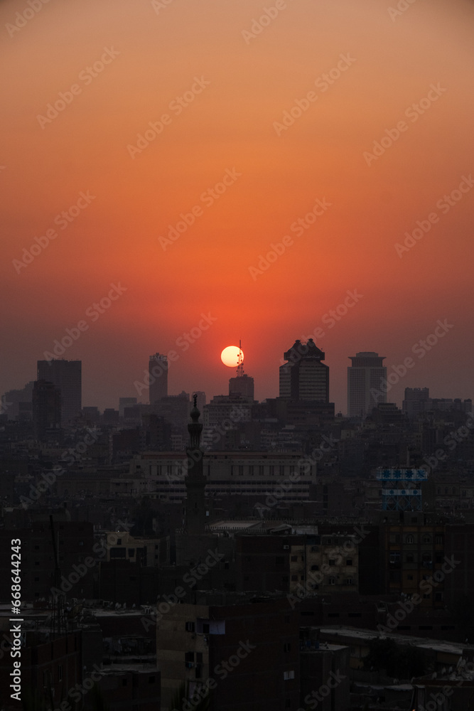 Orange and yellow open skies. Sunset over the city of Cairo in Egypt. Silhouette of the buildings in the metropolis. Neighborhood view of the cityscape.