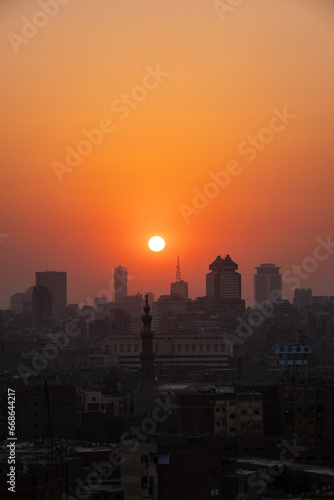 Orange and yellow open skies. Sunset over the city of Cairo in Egypt. Silhouette of the buildings in the metropolis. Neighborhood view of the cityscape. © Adrinson