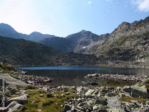 Panorama of beautiful Rila mountain landscape. Sunny day. Wonderful time landscape in mountains. Mountain lakes, grassy field and rolling hills.