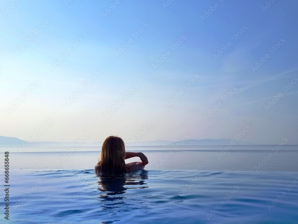 Fototapeta premium Portrait of a beautiful young woman relaxing in outdoor infinity swimming pool nearly sea beach in resort. vacation leisure wallpaper