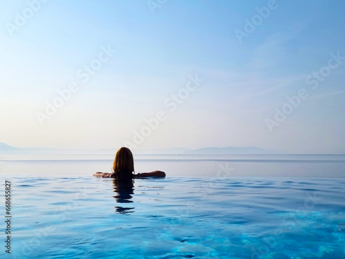 Portrait of a beautiful young woman relaxing in outdoor infinity swimming pool nearly sea beach in resort. vacation leisure wallpaper