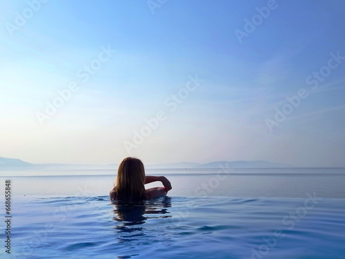 Portrait of a beautiful young woman relaxing in outdoor infinity swimming pool nearly sea beach in resort. vacation leisure wallpaper