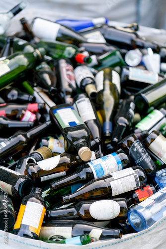 A large heavy bag with a huge amount of used glass bottles is prepared for their disposal at waste recycling station