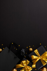 Hunting for christmas gift ideas. Top view vertical composition of gift boxes, package, festive ornaments, stars confetti on black background with promo area