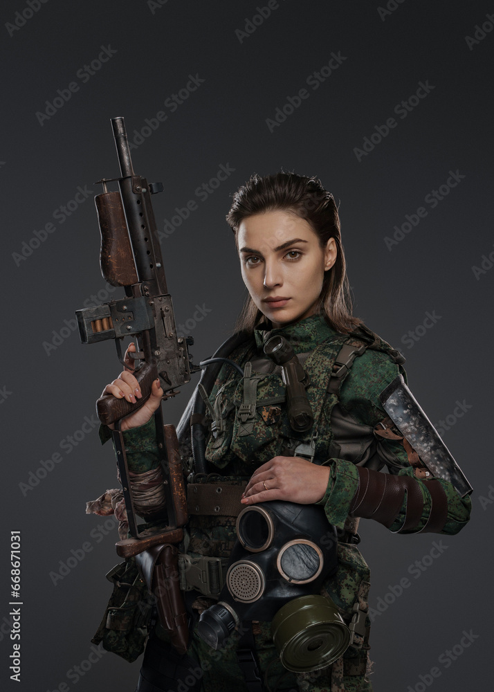 Portrait of a female soldier in military attire, holding a homemade automatic rifle, depicting a rebel or partisan in a Middle Eastern conflict against a gray background Portrait of a female soldier in military attire, holding a homemade automatic rifle, depicting a rebel or partisan in a Middle Eastern conflict against a gray background