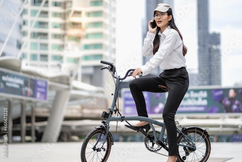 Eco friendly vehicle. 20s Businesswoman ride bicycle to work in urban. Cycling has no pollution, alternative energy to reduce carbon footprint. Environmental conservation by riding bike, green energy