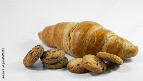 Chocolate chip cookies and croissants are placed in a wicker basket on a white cardboard background. Croissants on a white background. Chocolate chip cookies on a white background