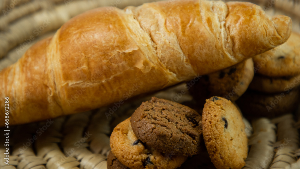 Chocolate chip cookies and croissants are placed in a wicker basket on a white cardboard background. Croissants on a white background. Chocolate chip cookies on a white background