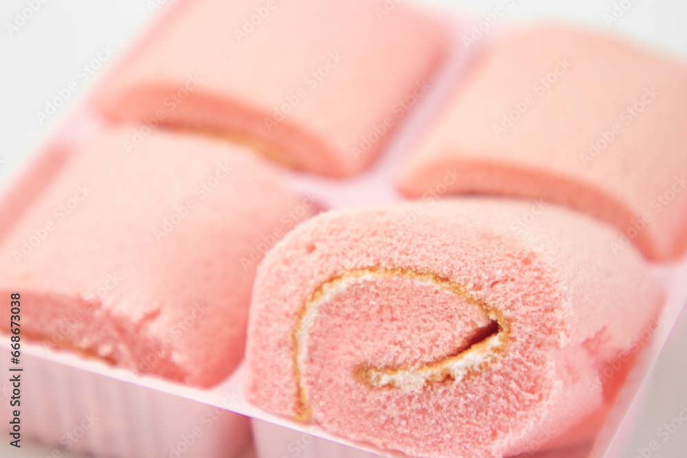 Fototapeta premium Strawberry roll cake on white background. Rose strawberry cake placed on a plate