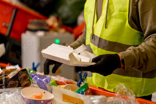 Fotografie Hands in gloves of a uniformed employee sort garbage into categories on a specia