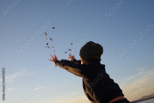 Bambino che lancia sassi (e le sue speranze) verso il cielo, verso l'orizzonte: verso il futuro! photo