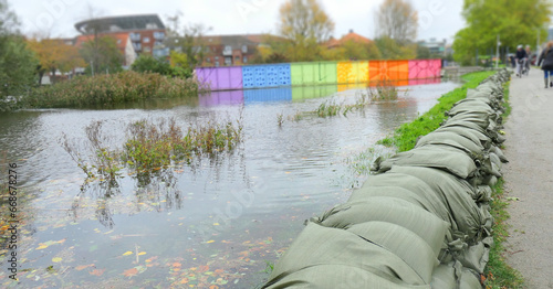 Sand bags barrier by city water stream with high water under autumn storm surge in Denmark